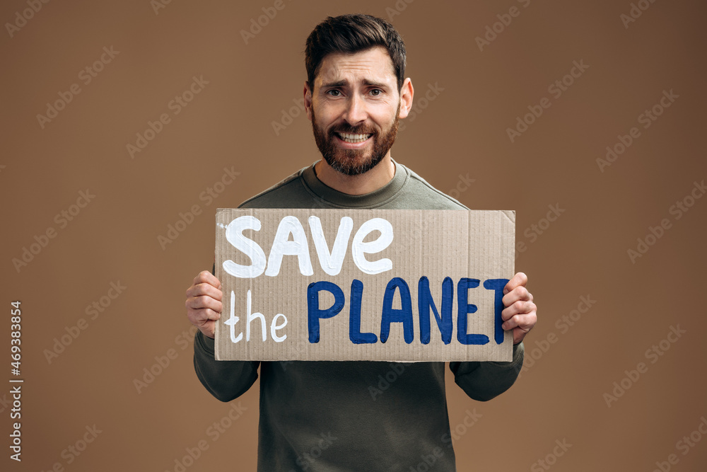 Waist up portrait view of the caucasian worried man holding carton placard with Save the Planet writing. Concept of nature destruction and eco activism Waist up portrait view of the caucasian worried man holding carton placard with Save the Planet writing. Concept of nature destruction and eco activism
