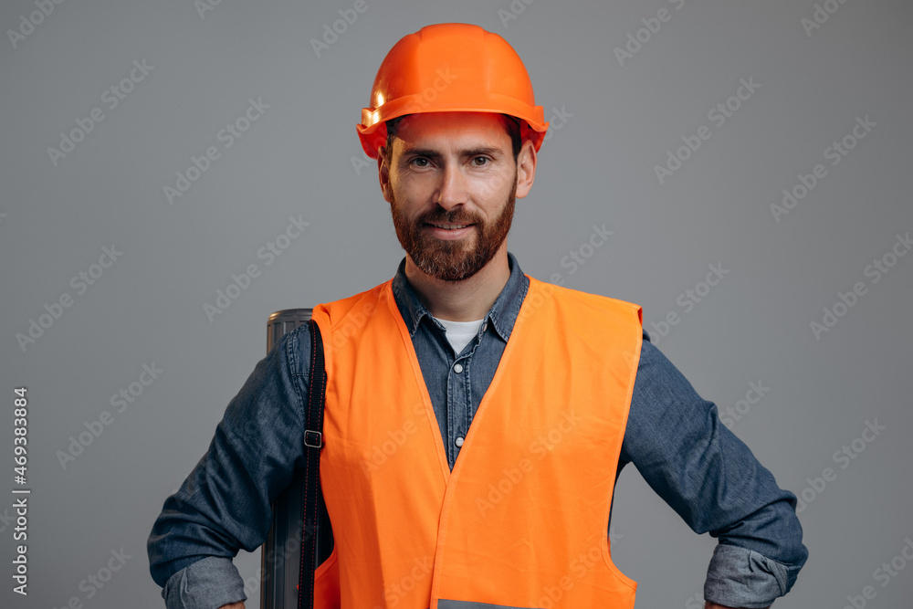 Business man engineer wearing safety helmet holding draft drawing construction behind the grey studio wall. Business concept Business man engineer wearing safety helmet holding draft drawing construction behind the grey studio wall. Business concept