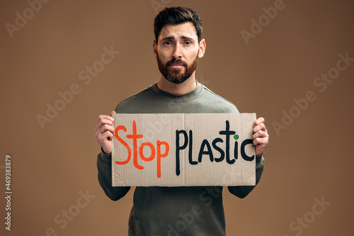 Caucasian worried sad man holding carton placard with Stop plastic writing. Concept of nature destruction and eco activism