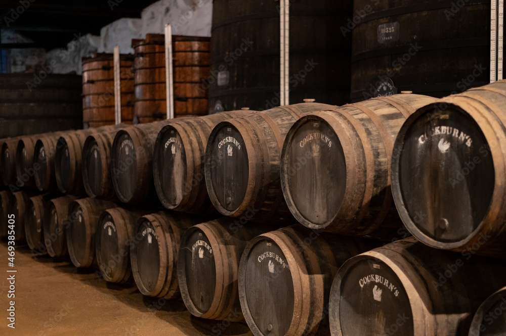 Old porto lodge with rows of oak wooden casks for slow aging of fortified ruby or tawny porto wine in Vila Nova de Gaia, Portugal