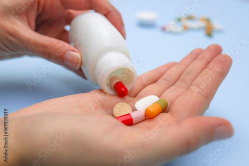 Close up of female pouring out different pills from ceramic white bottle into palm. Illness, therapy, sickness, medicine and health care concept.