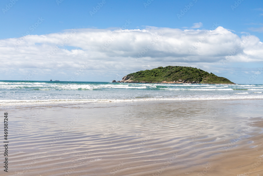 Beach view with sand, waves and island in background