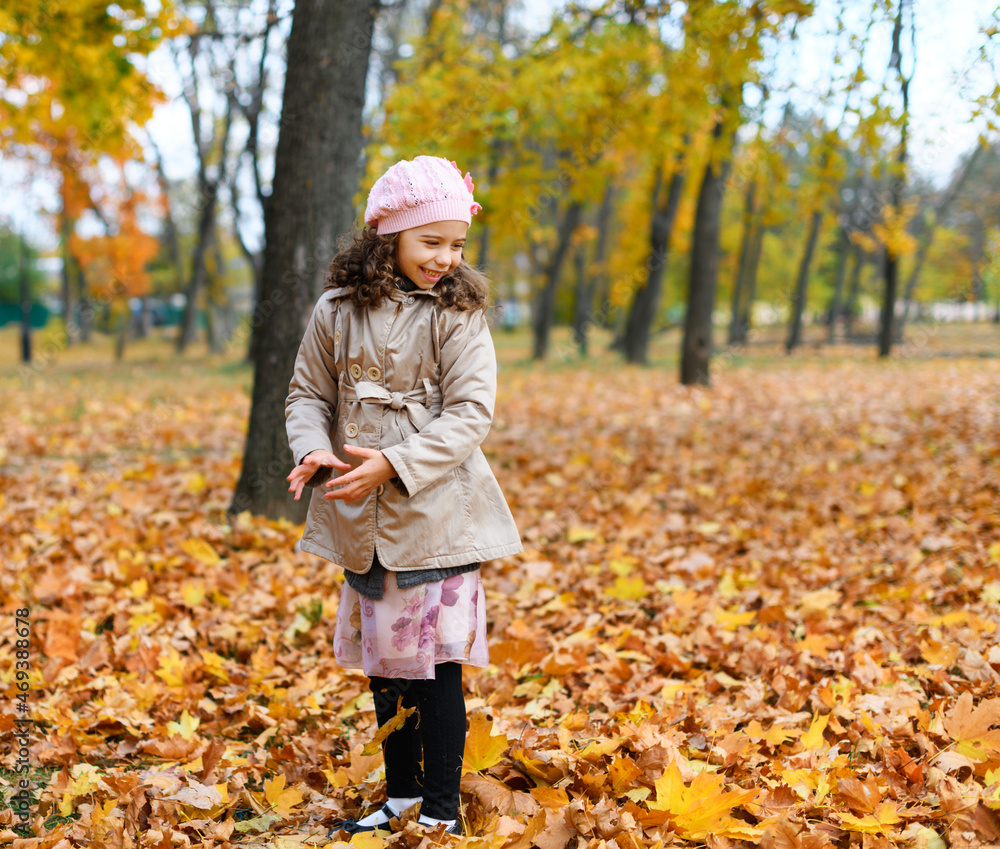 Girl playing with fallen yellow leaves. Portrait of a happy child in an autumn park. Girl playing with fallen yellow leaves. Portrait of a happy child in an autumn park.