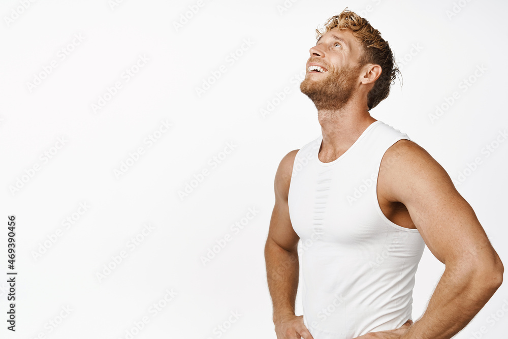 Image of smiling sportsman workout in gym, looking pleased after fitness training, standing over white background Image of smiling sportsman workout in gym, looking pleased after fitness training, standing over white background