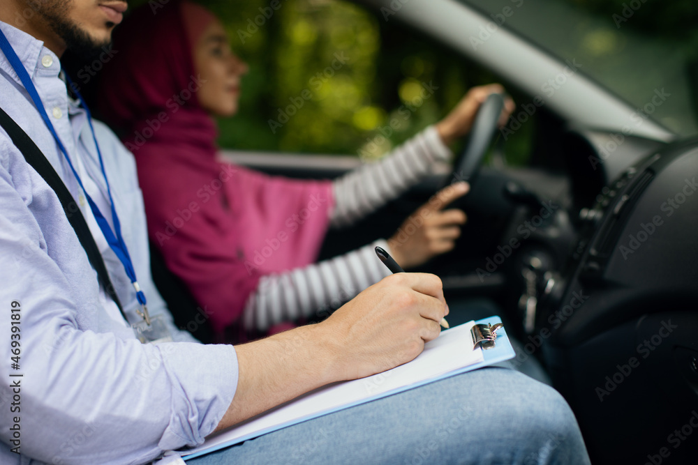 Driving School Concept. Male instructor examining muslim lady driver - obrazy, fototapety, plakaty 