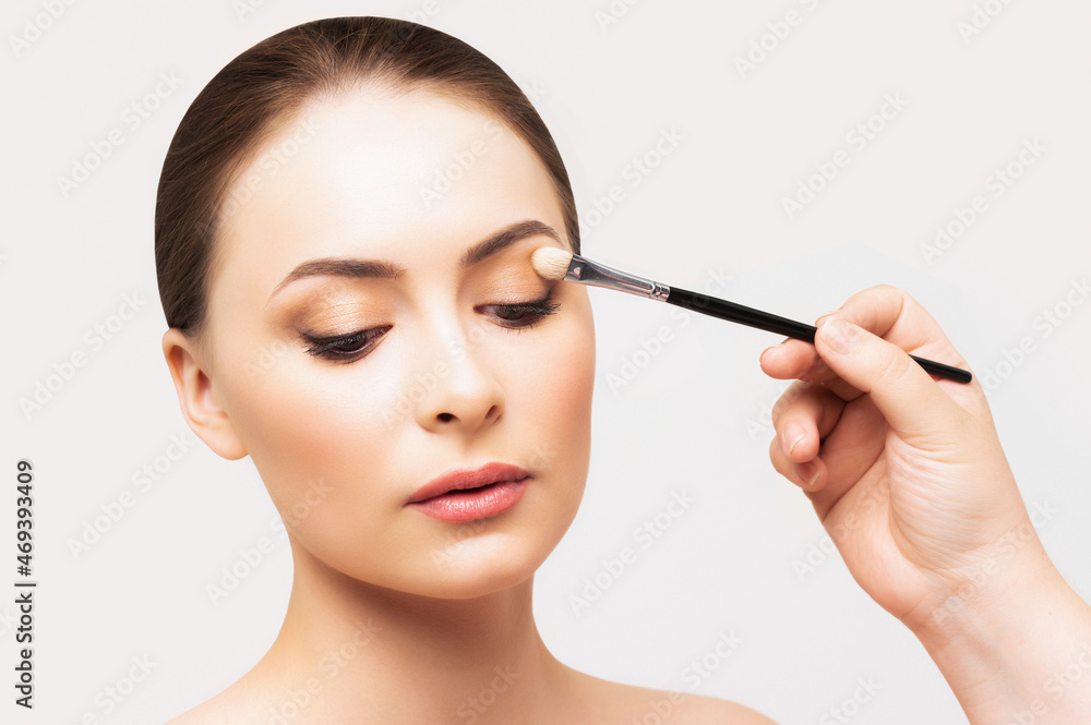 Model doing makeup. Make-up artist and beautiful woman. Girl face during make up