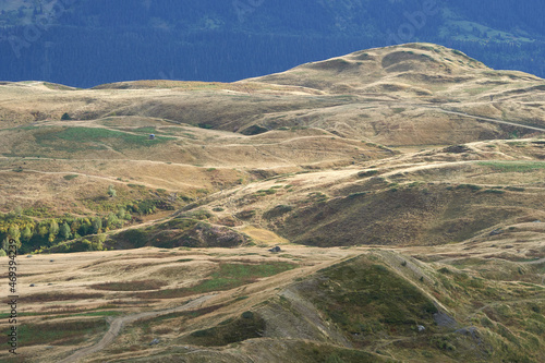 A hiker stands on a rocky outcrop in the Caucasus Mountains, Georgia, overlooking a vast and wild landscape. The sense of adventure and exploration is palpable in this remote and rugged setting. photo