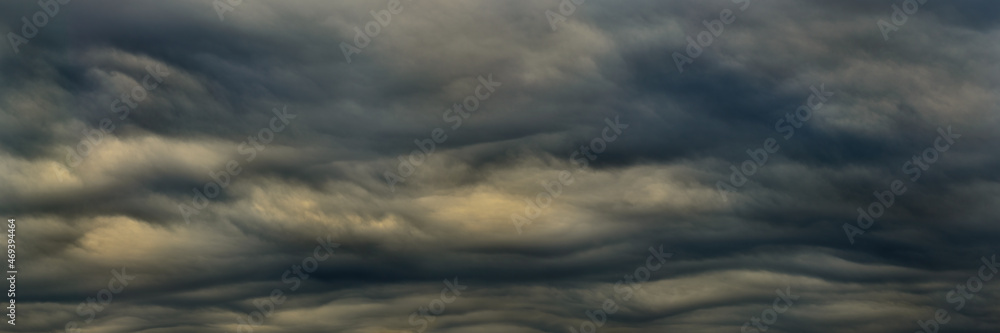 wide cloudy landscape. panoramic view of a gloomy dark sky with dense heavy clouds in atmospheric haze and faint backlight