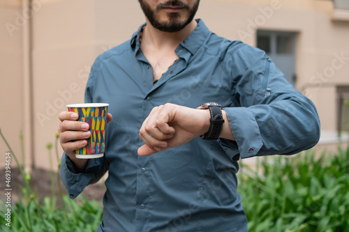 Joven hispano latino hombre de negocios con su café en la mano, mirando la hora