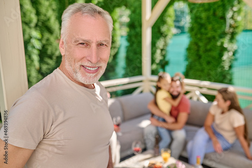 A gray-haired man standing and looking happy