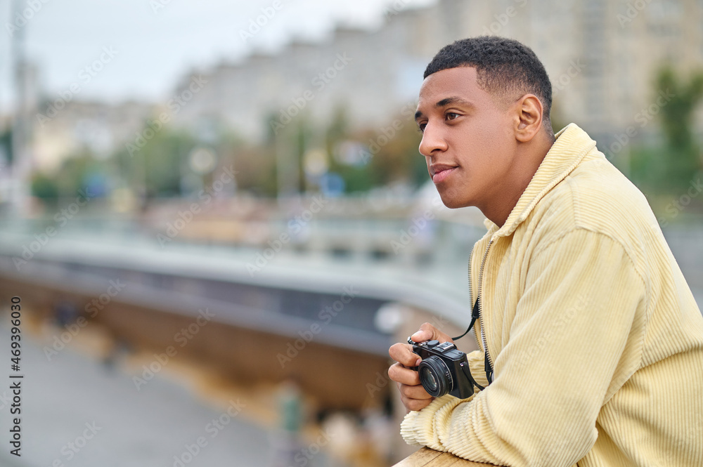 Dark-haired attractive photographer standing with a thoughtful look Dark-haired attractive photographer standing with a thoughtful look