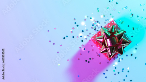 Christmas composition neon. Xmas gift box with shine lights. Holiday decoration on neon abstract gradient backdrop. New year banner.