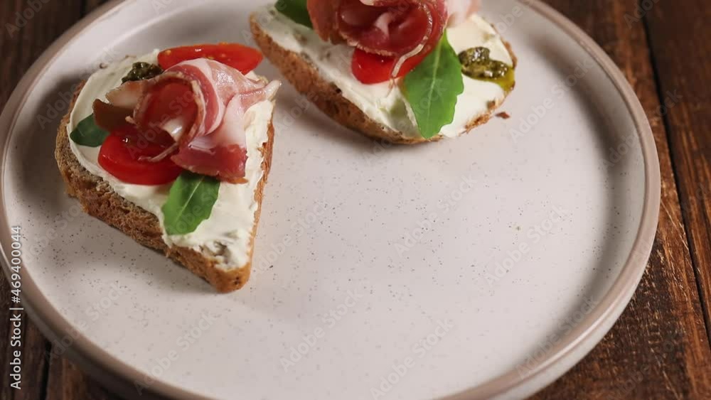 Woman hand takes ham cheese sandwich from plate, eating bruschetta for breakfast, close up Woman hand takes ham cheese sandwich from plate, eating bruschetta for breakfast, close up