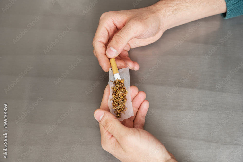 Hands rolling a laugh-making cigarette with thin rice paper Hands rolling a laugh-making cigarette with thin rice paper