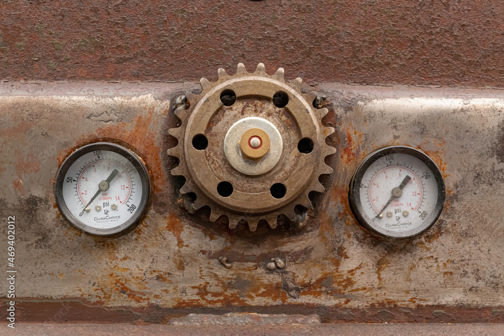 Gritty, rusty cog-wheel gear and pressure gauges on a beat up classic car in need of restoration 