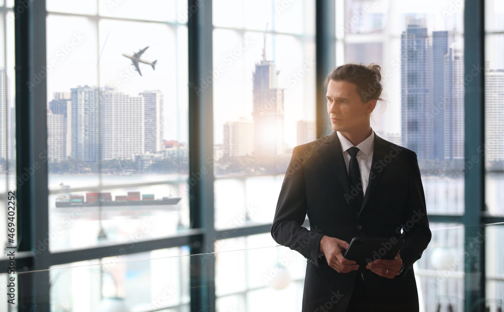 Handsome businessman in suit is standing at office with airplane or logistics business background Handsome businessman in suit is standing at office with airplane or logistics business background