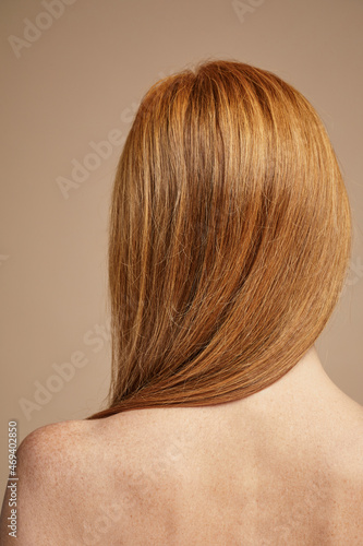 Minimal back view of freckled red haired woman with nude shoulders