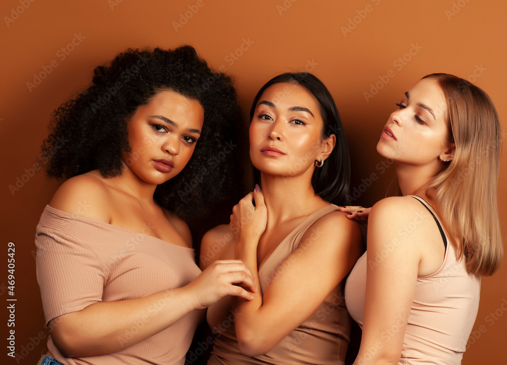 young pretty asian, caucasian, afro woman posing cheerful together on brown background, lifestyle diverse nationality people concept young pretty asian, caucasian, afro woman posing cheerful together on brown background, lifestyle diverse nationality people concept
