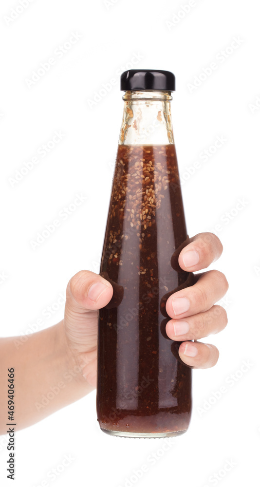 Hand holding spicy sauces in glass bottles isolated on a white background. Hand holding spicy sauces in glass bottles isolated on a white background.