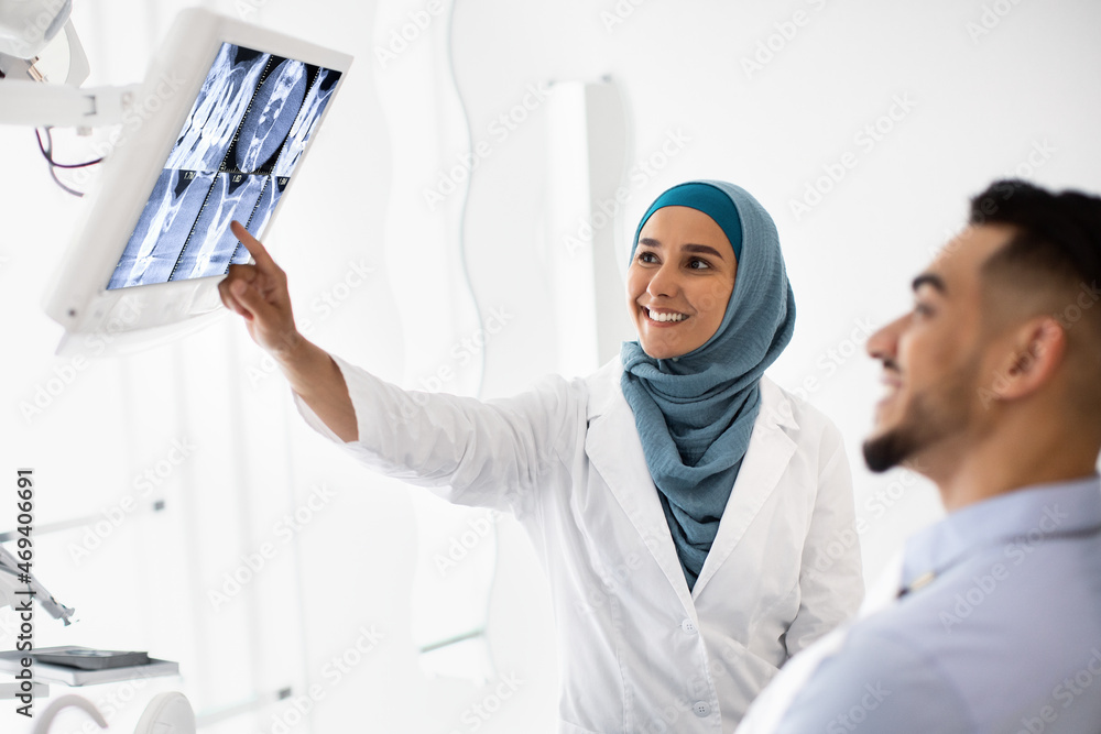 Obraz premium Islamic Dentist Lady Showing Teeth Xray On Digital Monitor To Male Patient