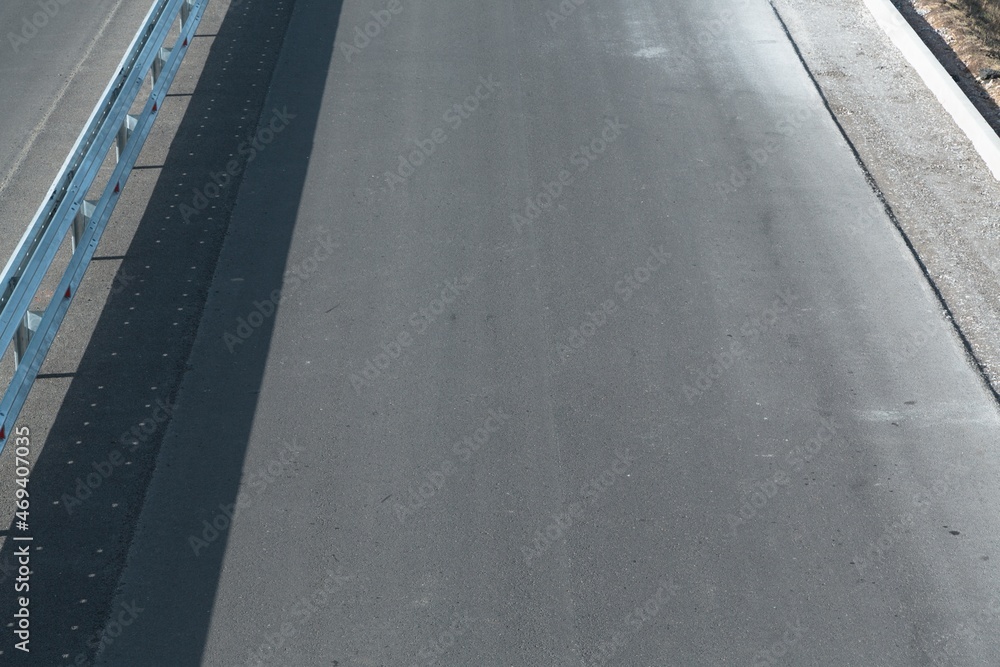 Fototapeta premium Panorama view of an endless straight road running through the barren scenery on a sunny day
