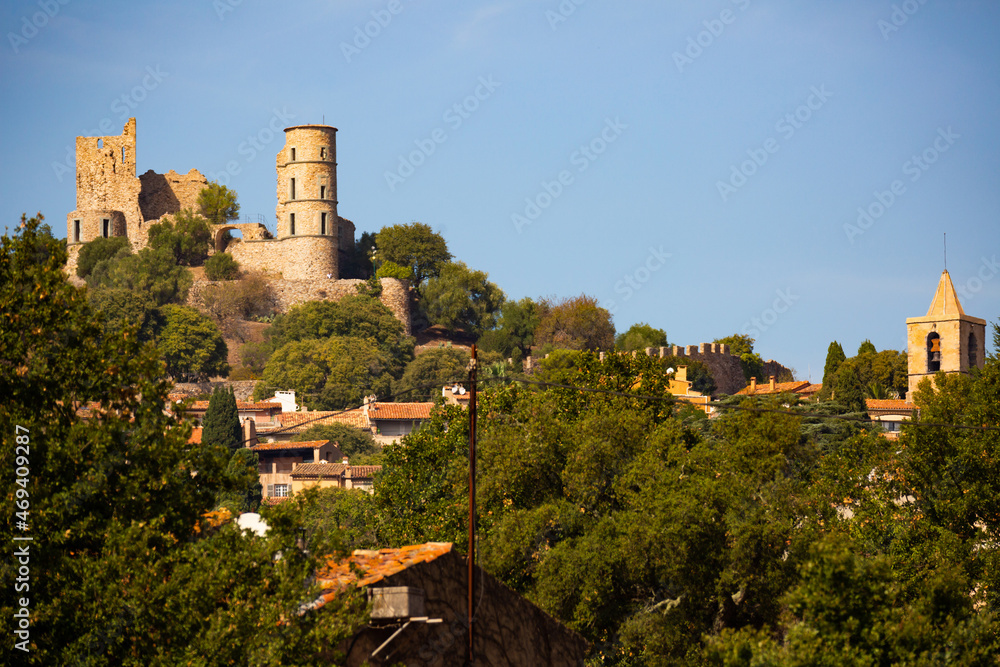 Scenic view of ruins of ancient fortified castle of Grimaud on hill dominating residential houses of village on sunny autumn day, Var department, France