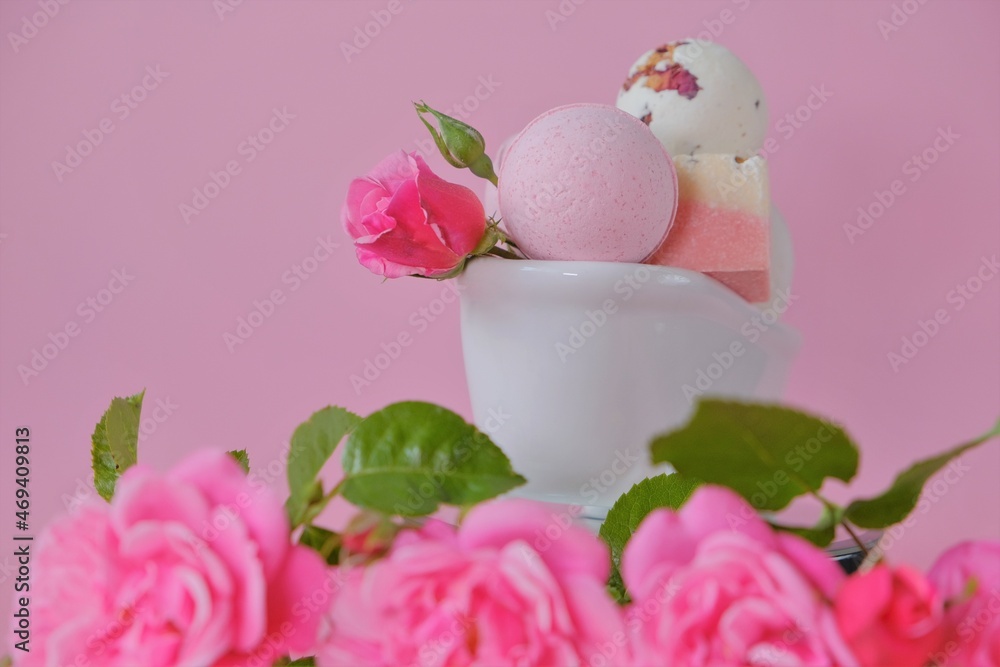 Bath bombs with rose extract in a ceramic bath and pink roses on a pink background. Flower Bath Bombs.Organic vegan eco cosmetics. Beauty and aromatherapy. Bath bombs with rose extract in a ceramic bath and pink roses on a pink background. Flower Bath Bombs.Organic vegan eco cosmetics. Beauty and aromatherapy.