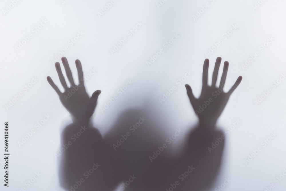 Blurry silhouette of person touching glass with hands Blurry silhouette of person touching glass with hands