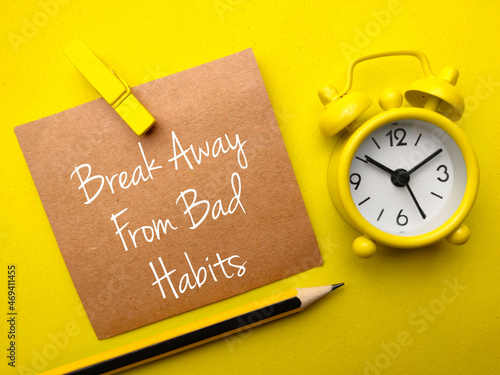Pencil,clock and brown card with text Break away from bad habits on yellow background.