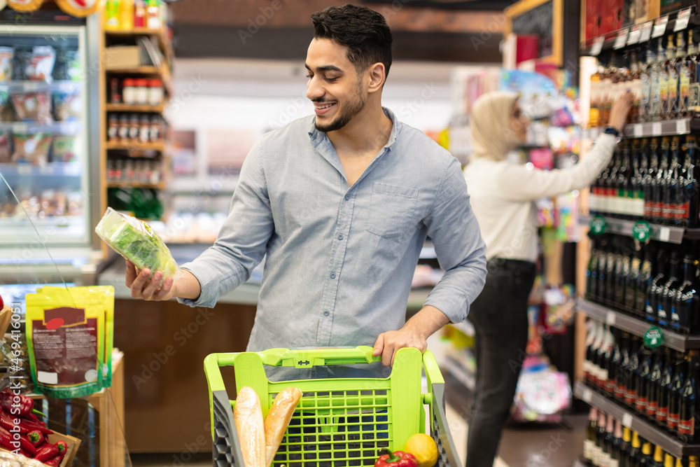 Arabic Male Doing Grocery Shopping Choosing Vegetables In Modern Supermarket