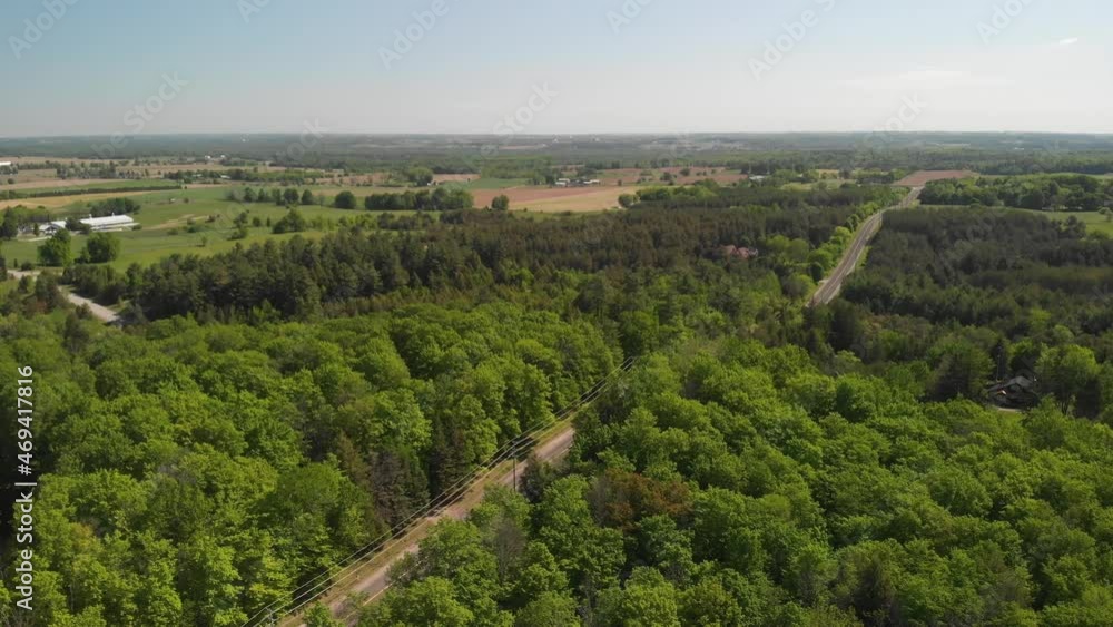A aerial shot drift over a country road which cuts a path through a dense forest. A aerial shot drift over a country road which cuts a path through a dense forest.