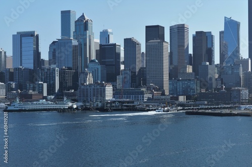 City skyline of Seattle and passenger ferry in port situated on Puget Sound with skyscrapers  view from container vessel sailing from cargo terminal to pacific ocean during sunny autumn weather.