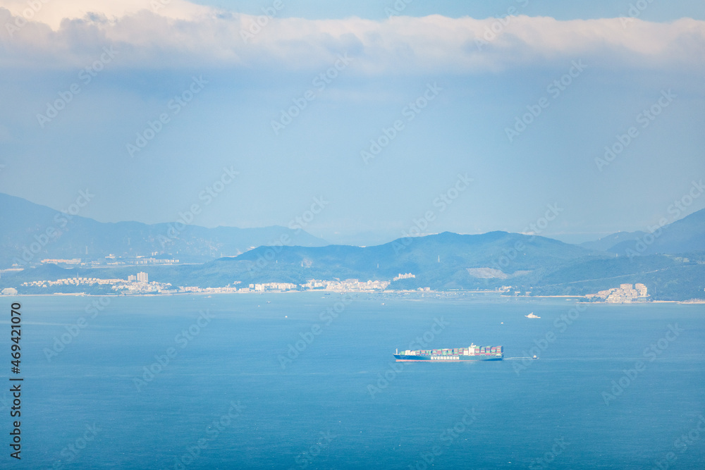 Cargo Container Ship on the sea near the coast and mountains