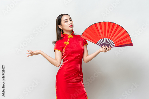 Beautiful Asian woman in red oriental style qipao dress holding fan on light gray isolated background photo
