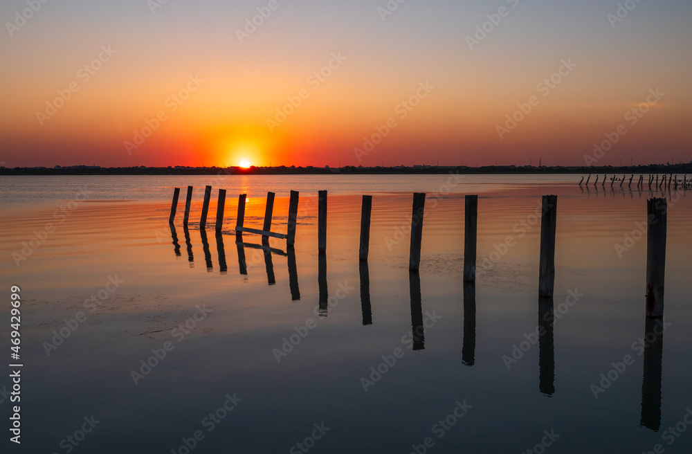 Beautiful red and orange sunset over the sea. The sun goes down over the sea. An old sea pier in orange sunset light
