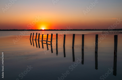 Beautiful red and orange sunset over the sea. The sun goes down over the sea. An old sea pier in orange sunset light