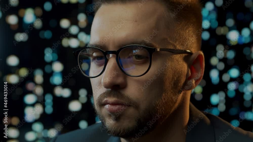 Close-up portrait of a young man working at the computer. Laptop display is reflected in glasses. Night city lights on the background. Business, coding and exchange concept. Close-up portrait of a young man working at the computer. Laptop display is reflected in glasses. Night city lights on the background. Business, coding and exchange concept.