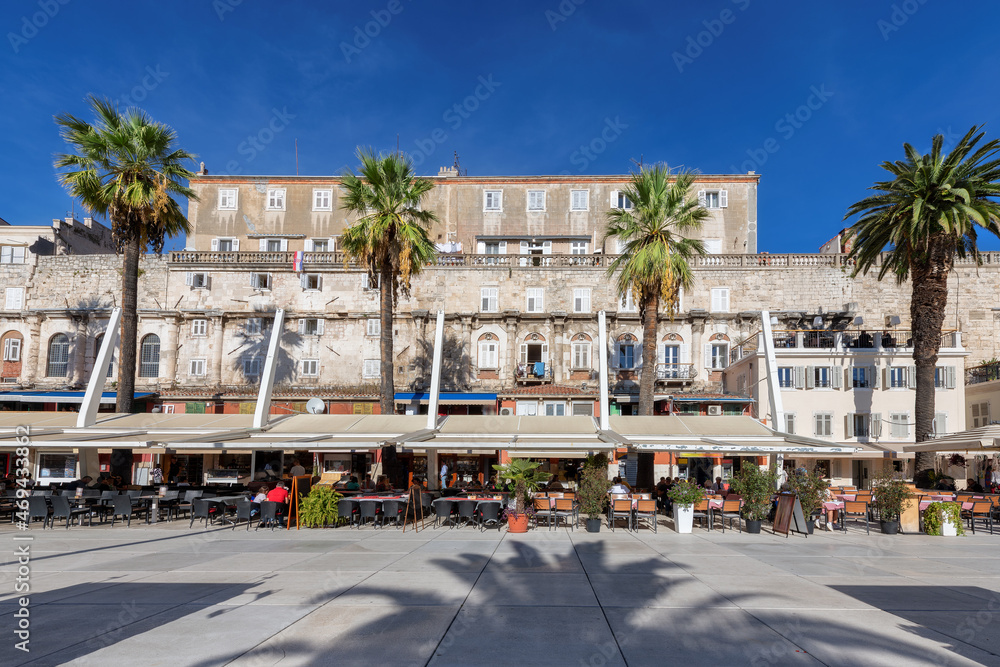 Old town of Split with stone wall, palm trees, cafe and restaurant in Riva promenade, Split, Croatia. 