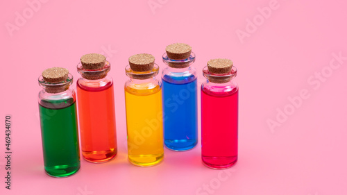 Liquid of different colors are poured into glass bottles with wooden corks