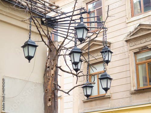 A vintage lanterns on a stone wall in front of windows in Lviv. Street lighting. Beautiful old Iron lamps on the corner against old stone pictorial street old town near central square Lviv, Ukraine. 