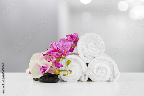 Towels with flowers on light table against blurred background