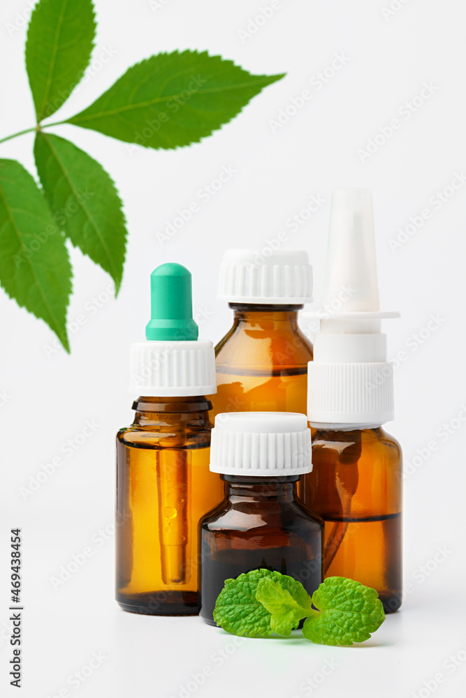 Essential oil in a small bottle with green leaf on white background Essential oil in a small bottle with green leaf on white background