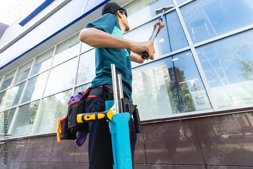 An employee of a professional cleaning service in overalls washes the glass of the windows of the facade of the building. Showcase cleaning for shops and businesses photo