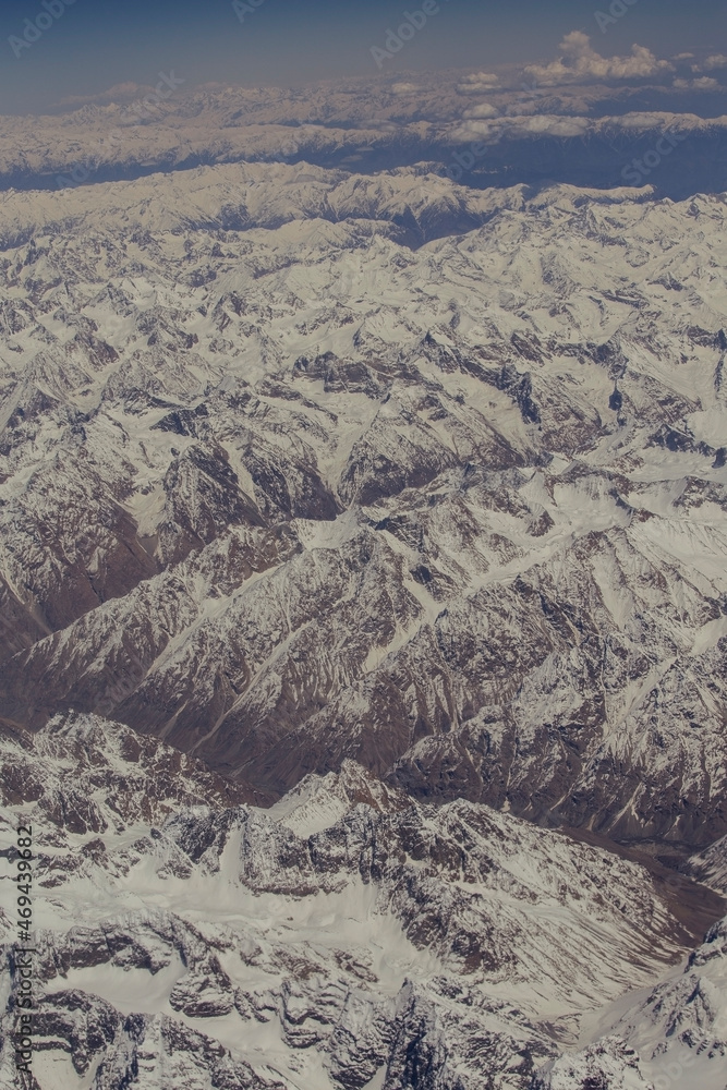 Aerial views in mountain. View from the plane window. The Hindu Kush mountain system in Afghanistan
