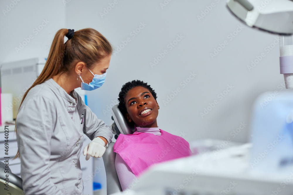 Female patient sitting in the dental chair and talking to her dentist Female patient sitting in the dental chair and talking to her dentist