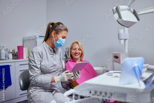 Dentist showing x ray image on digital tablet to patient