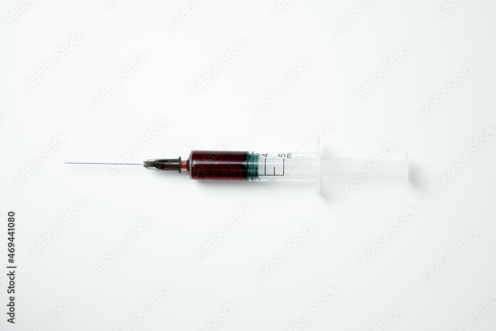 Medical syringe and needle with red blood on a light background Medical syringe and needle with red blood on a light background