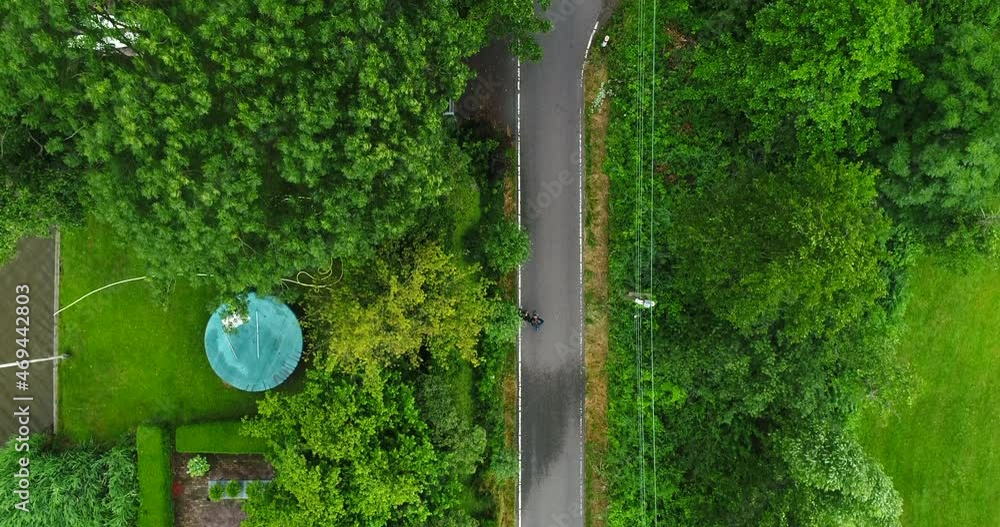 Two People Walking Together In A Narrow Walkway In A Park Next To A Pond Surrounded By Lush Green Trees And Grasses At Reeuwijkse Plassen, Netherlands. - Aerial Drone Shot Two People Walking Together In A Narrow Walkway In A Park Next To A Pond Surrounded By Lush Green Trees And Grasses At Reeuwijkse Plassen, Netherlands. - Aerial Drone Shot