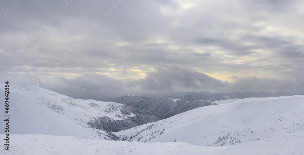 Panoramic view to snow-covered mountain slopes at sunset. Winter landscape. Carpathian Mountains.
