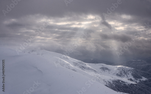 Snow covered slopes under a cloudy sky.